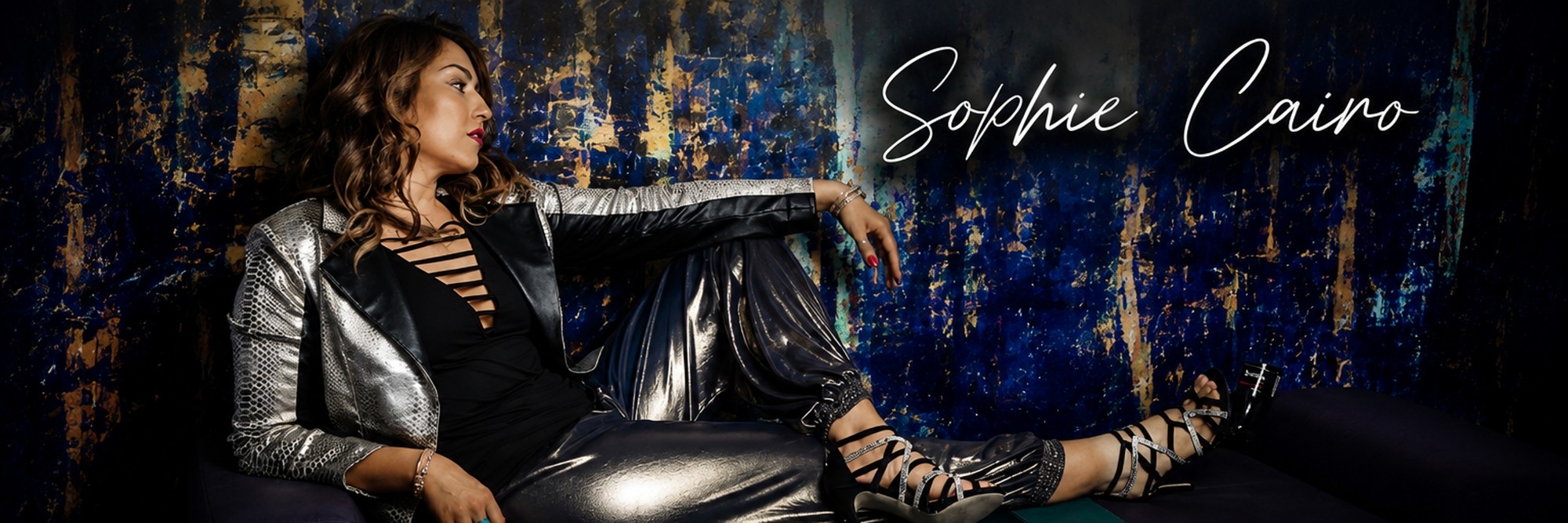 Sophie Cairo in a silver jacket against a blue and gold backdrop